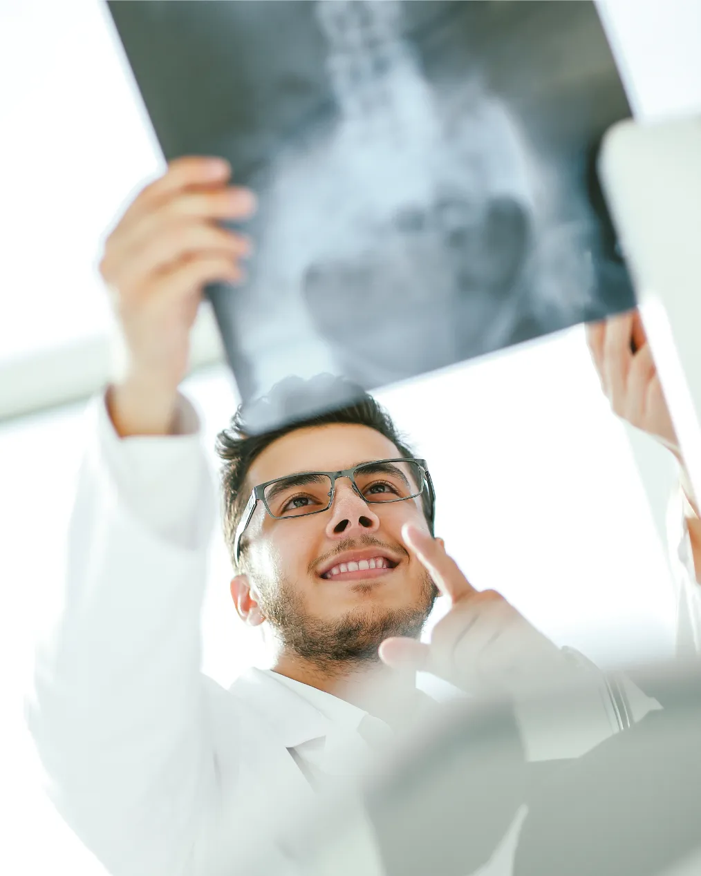Smiling orthopedist doctor looks x ray patient photo with copy space